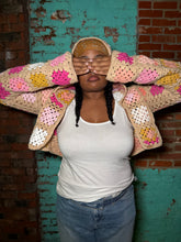 Load image into Gallery viewer, Person wearing a colorful crochet jacket against a brick wall.