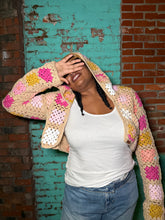 Load image into Gallery viewer, Person wearing a colorful crochet hoodie in front of a textured wall.